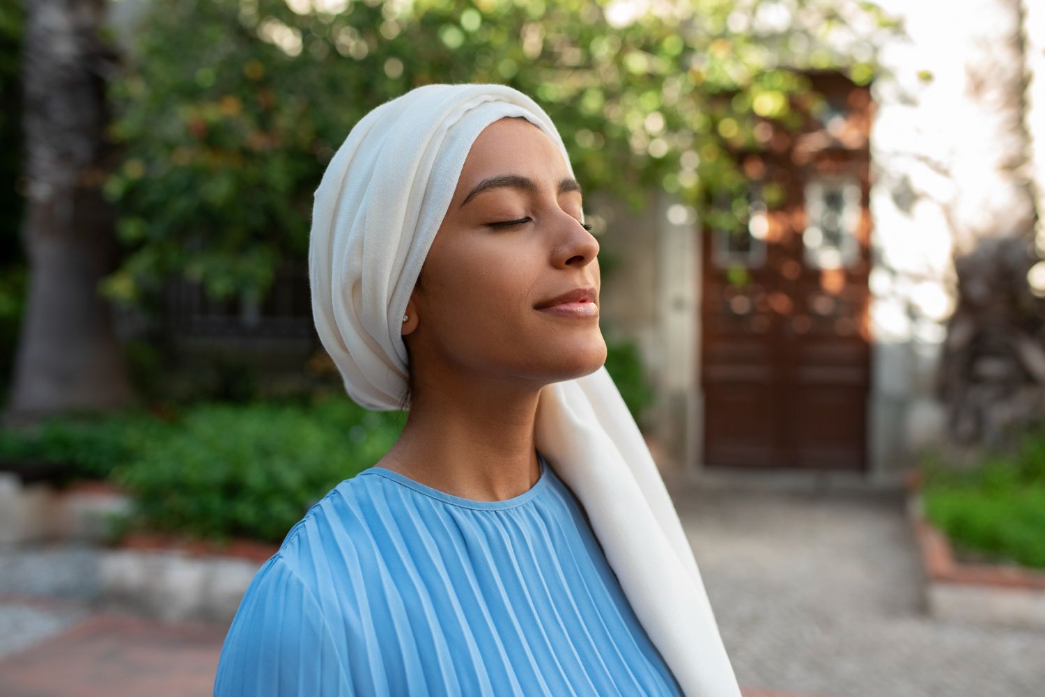 A woman in a headscarf resting peacefully outdoors