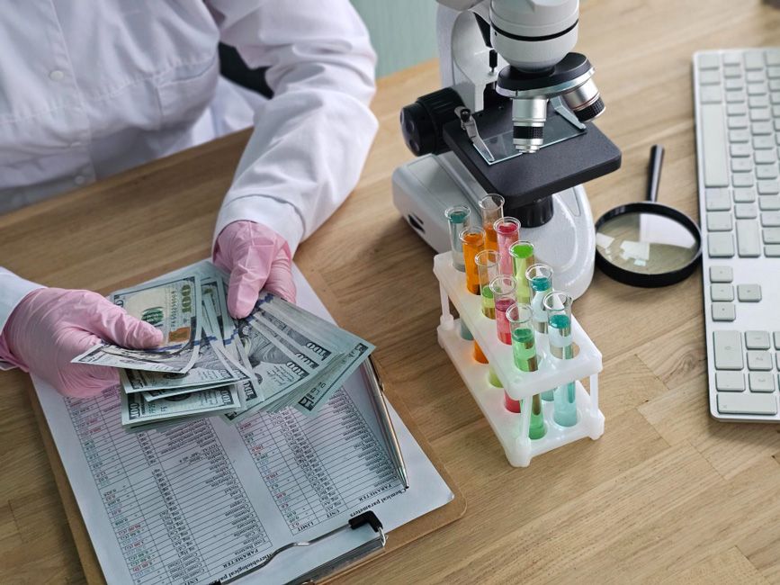 A researcher with a microscope, test tubes and funds