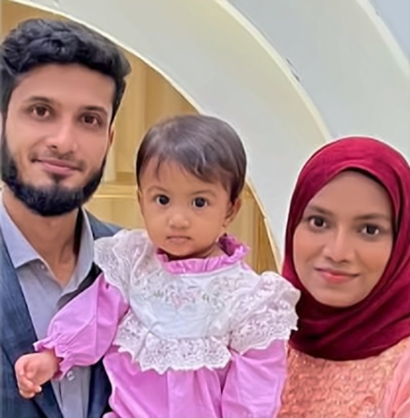 Aiesha in a pink lace dress with her father and mother